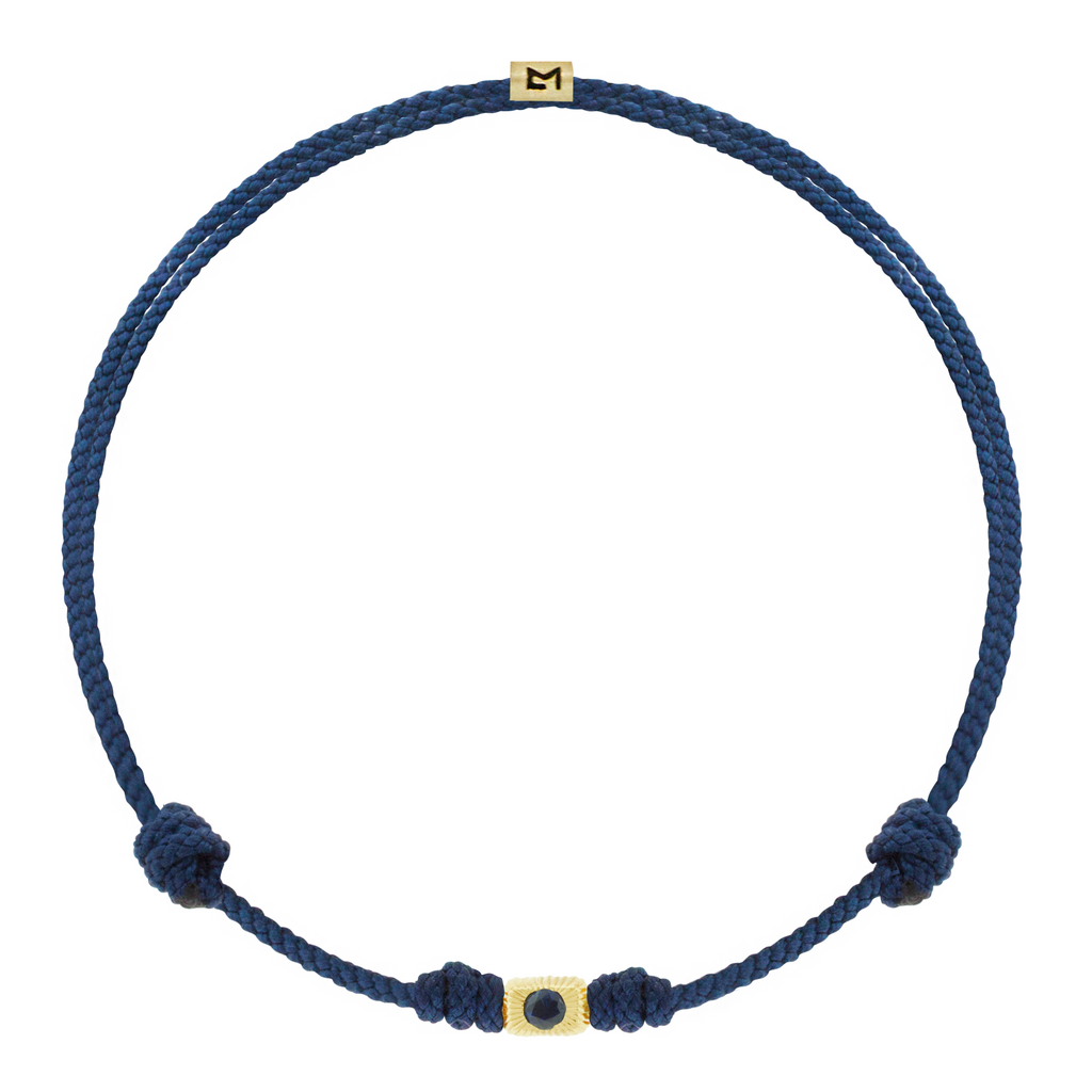 LUIS MORAIS 14k yellow gold small corrugated ingot with a blue sapphire on a cord bracelet. Gold logo spacer.